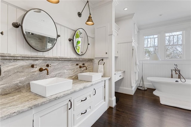 bathroom featuring a sink, tasteful backsplash, wood finished floors, and crown molding