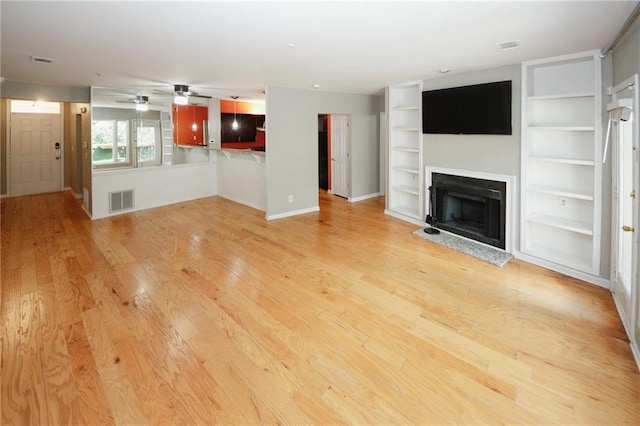 485 Sherman Way, Decatur, GA 30033 - unfurnished living room featuring light wood-type flooring, a fireplace with raised hearth, ceiling fan, and built in shelves