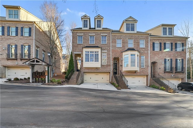 view of property featuring stairs, driveway, brick siding, and an attached garage