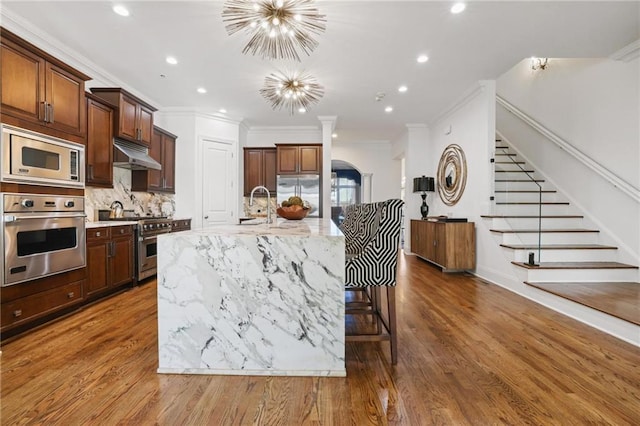 538 Sarabrook Pl NE, Sandy Springs, GA 30342 - kitchen with built in appliances, under cabinet range hood, decorative backsplash, a chandelier, and recessed lighting