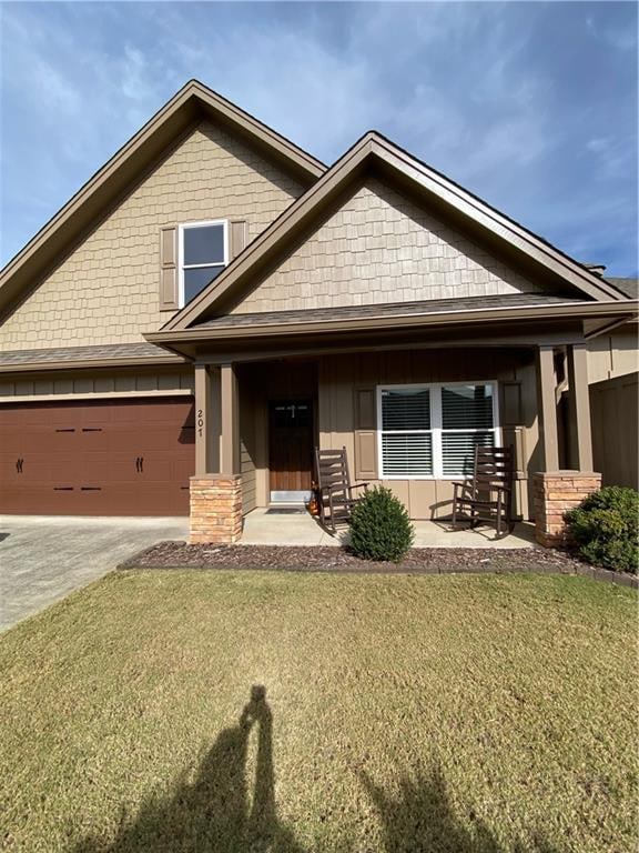 craftsman-style home with a front yard, a garage, and covered porch