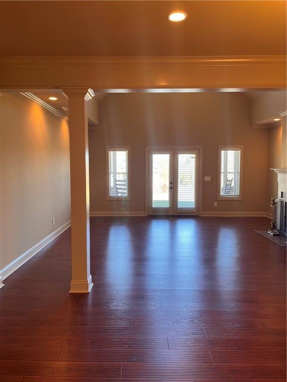 unfurnished living room with ornate columns, crown molding, dark hardwood / wood-style flooring, and french doors