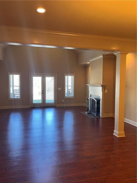 unfurnished living room with french doors, crown molding, and dark wood-type flooring