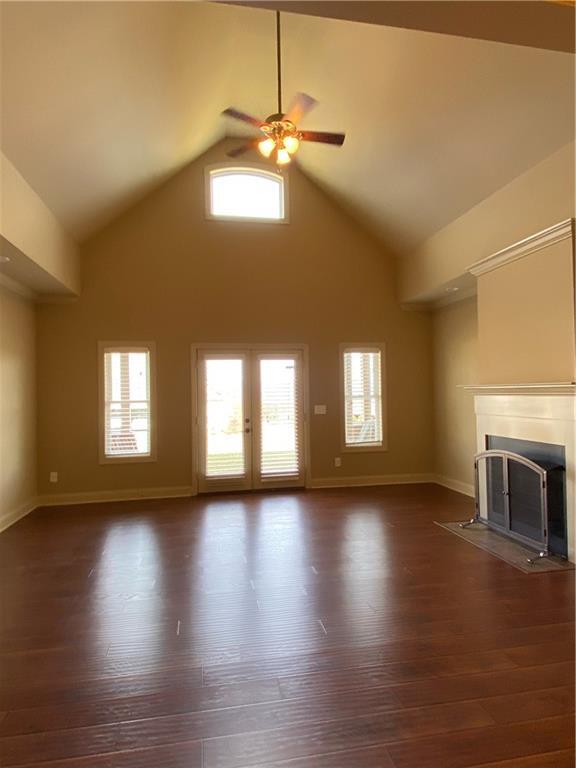 unfurnished living room featuring ceiling fan, dark hardwood / wood-style flooring, and high vaulted ceiling