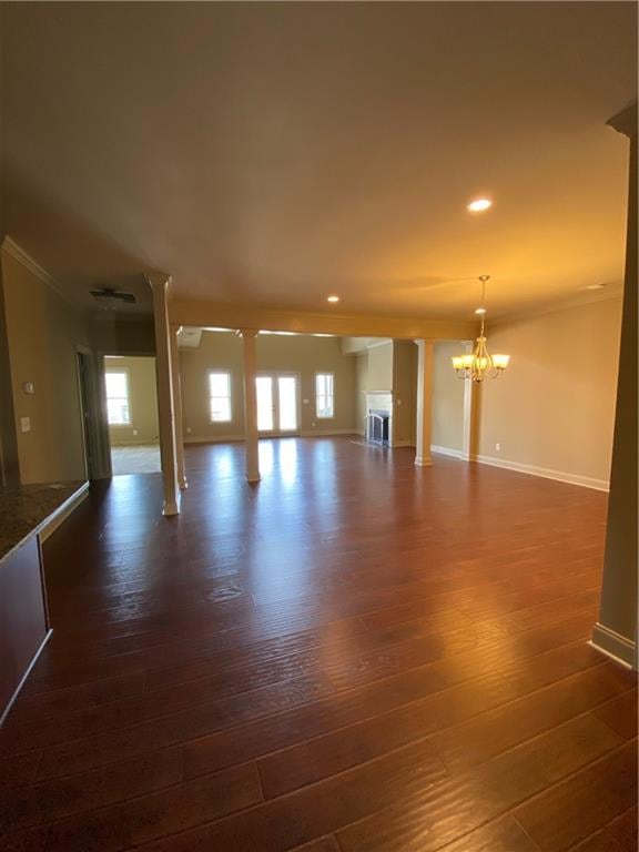 unfurnished living room featuring ornamental molding, dark hardwood / wood-style floors, and a notable chandelier