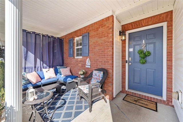 entrance to property featuring a porch and brick siding