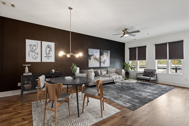 dining area featuring ceiling fan with notable chandelier and hardwood / wood-style flooring