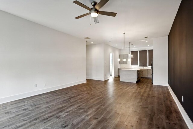 unfurnished living room featuring dark hardwood / wood-style floors, ceiling fan, and sink