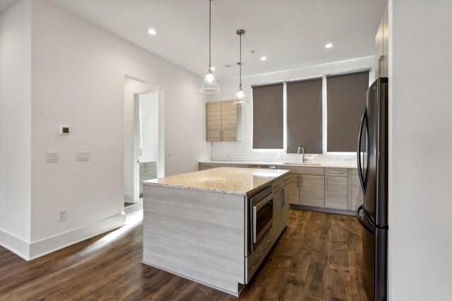 kitchen with a center island, hanging light fixtures, light stone counters, dark hardwood / wood-style floors, and appliances with stainless steel finishes