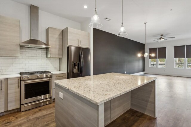 kitchen featuring light stone countertops, wall chimney exhaust hood, stainless steel appliances, ceiling fan, and dark hardwood / wood-style floors