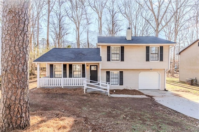 tri-level home featuring driveway, a porch, an attached garage, central AC unit, and a chimney