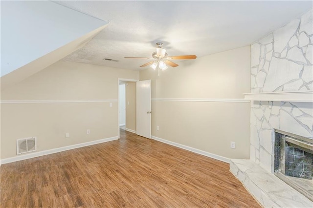 unfurnished living room featuring visible vents, baseboards, a stone fireplace, and wood finished floors