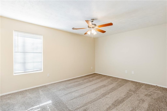 carpeted spare room with a ceiling fan, baseboards, and a textured ceiling