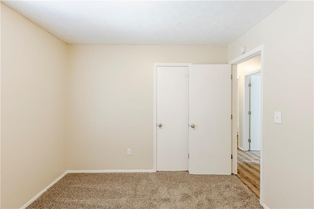 unfurnished bedroom featuring baseboards and light carpet