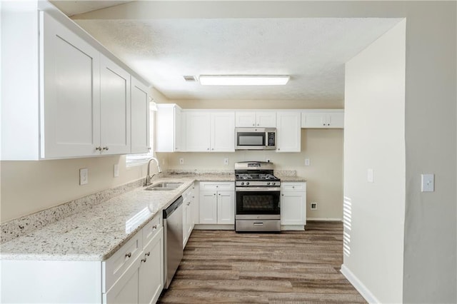 kitchen with appliances with stainless steel finishes, white cabinetry, and a sink