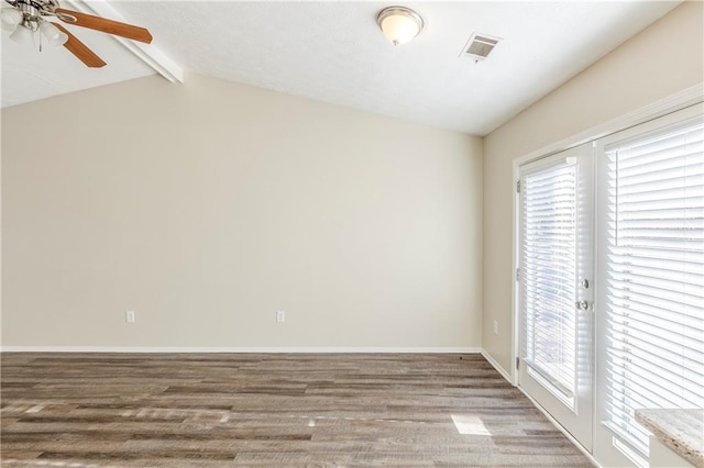 spare room with visible vents, a ceiling fan, wood finished floors, baseboards, and vaulted ceiling with beams