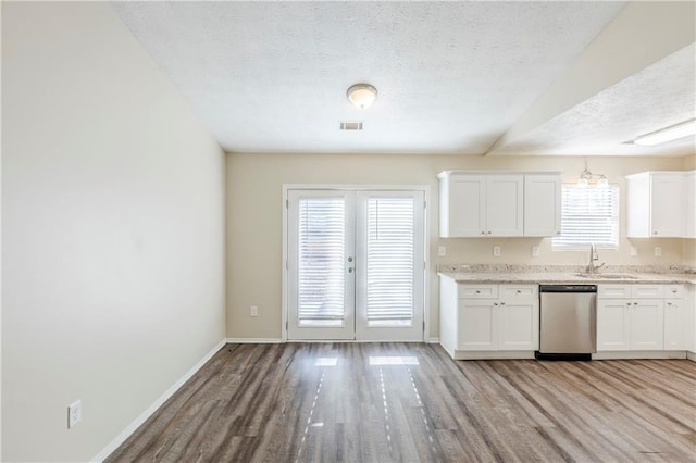 kitchen with visible vents, light wood-style flooring, stainless steel dishwasher, a textured ceiling, and a sink