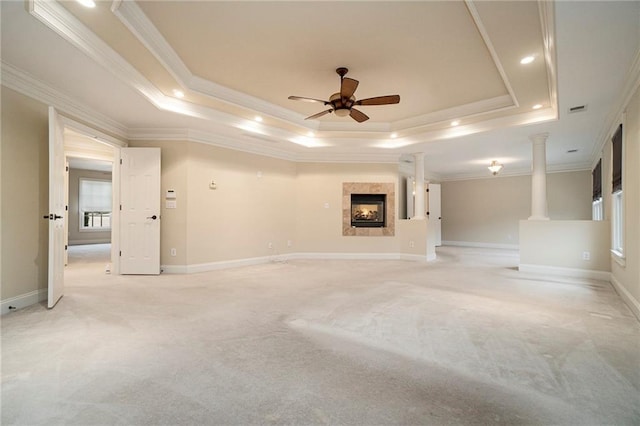 unfurnished living room with a raised ceiling, crown molding, light colored carpet, and decorative columns