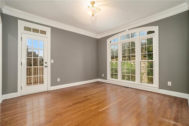 spare room with wood-type flooring, ornamental molding, and a wealth of natural light