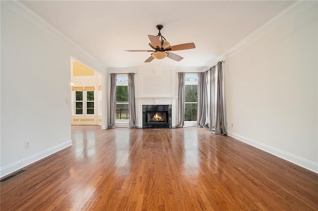 unfurnished living room with hardwood / wood-style floors, ornamental molding, and ceiling fan