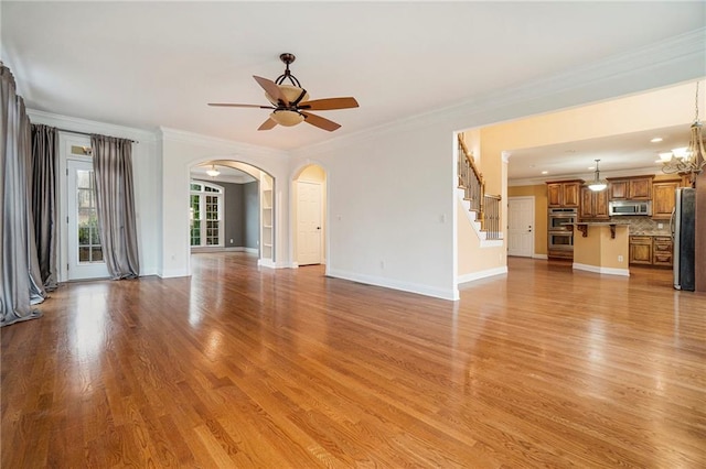 unfurnished living room with crown molding, light hardwood / wood-style floors, and ceiling fan with notable chandelier