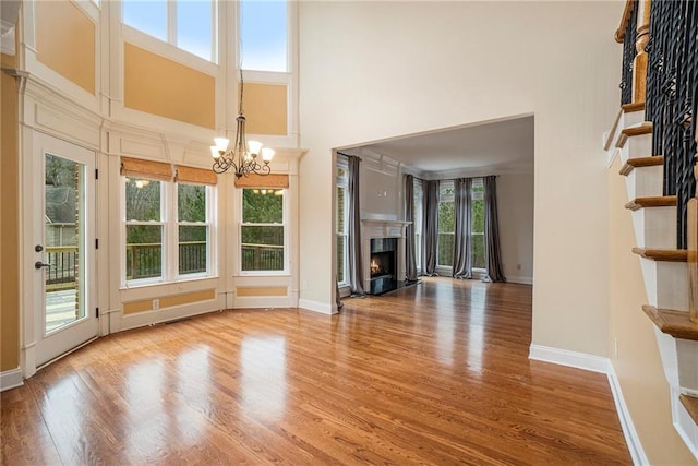 unfurnished living room with an inviting chandelier, hardwood / wood-style flooring, and a towering ceiling