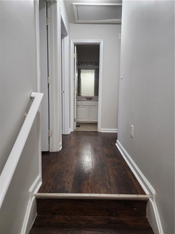 hall featuring dark wood-type flooring and baseboards