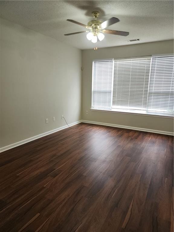 empty room with visible vents, baseboards, ceiling fan, a textured ceiling, and dark wood-style floors
