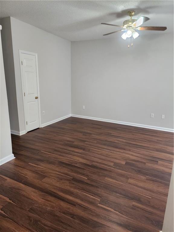 empty room with dark wood-type flooring, a textured ceiling, baseboards, and a ceiling fan