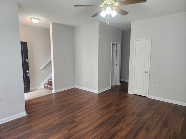 unfurnished room featuring wood finished floors, baseboards, a ceiling fan, and stairs