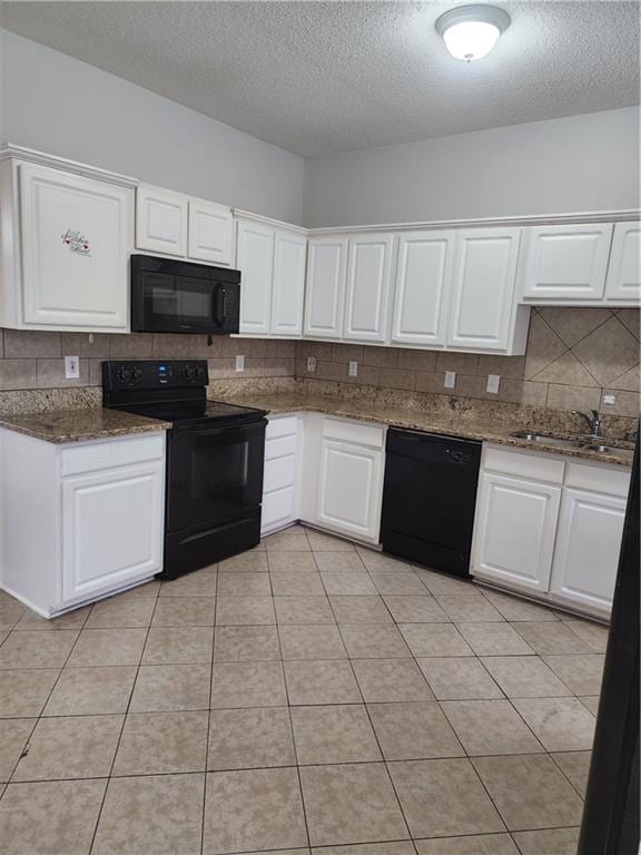 kitchen with light tile patterned floors, white cabinets, black appliances, a sink, and decorative backsplash