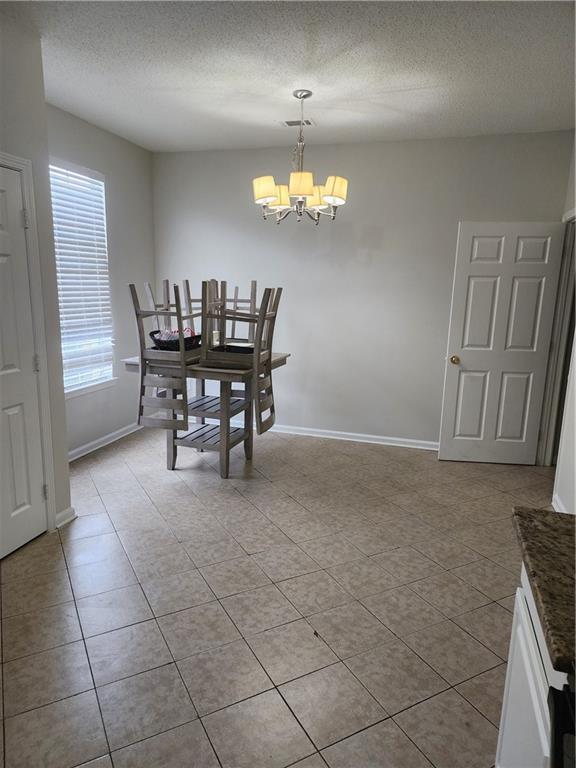 kitchen with tasteful backsplash, light tile patterned floors, white cabinets, and black appliances