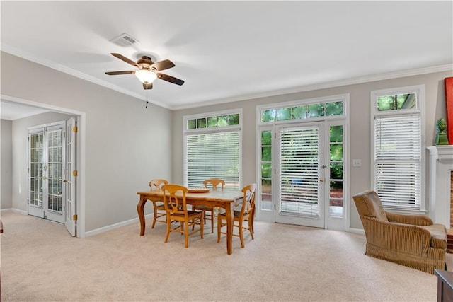 dining space with ornamental molding, french doors, light colored carpet, and a healthy amount of sunlight