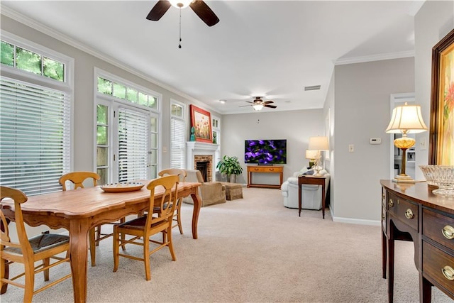 dining area with light carpet, ornamental molding, a brick fireplace, and baseboards