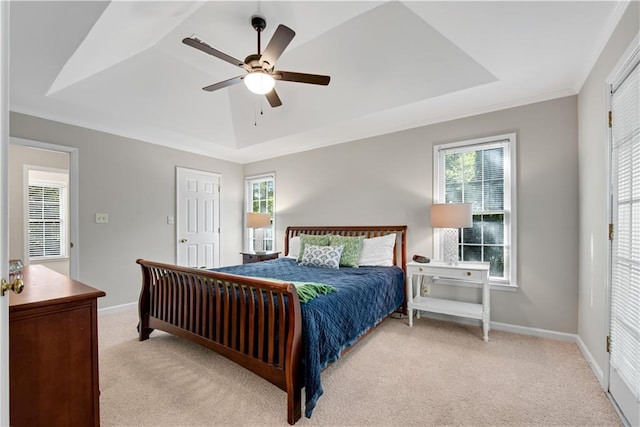 bedroom featuring a raised ceiling, light carpet, and multiple windows