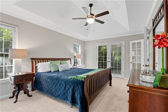 bedroom with light carpet, a tray ceiling, french doors, and multiple windows