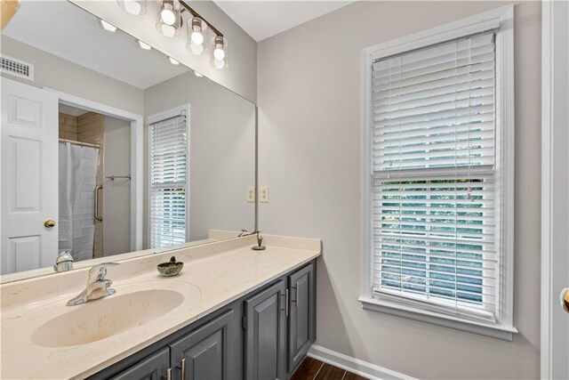 full bath featuring curtained shower, visible vents, vanity, and baseboards