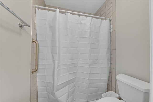 bathroom with a shower with shower curtain and toilet