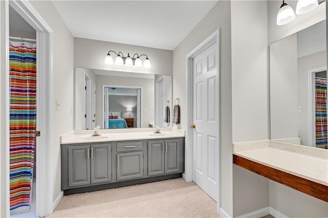 ensuite bathroom with ensuite bathroom, double vanity, a sink, and baseboards