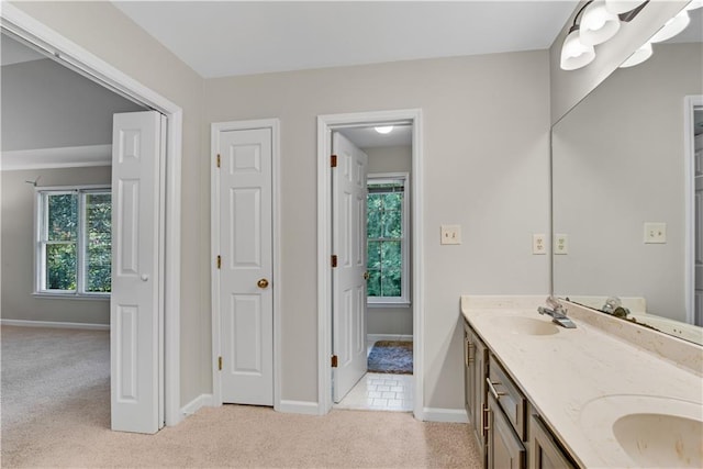 full bath featuring double vanity, carpet floors, a sink, and baseboards