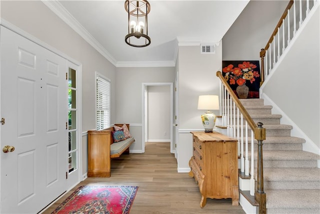 entryway with crown molding, a notable chandelier, visible vents, light wood-style flooring, and stairway