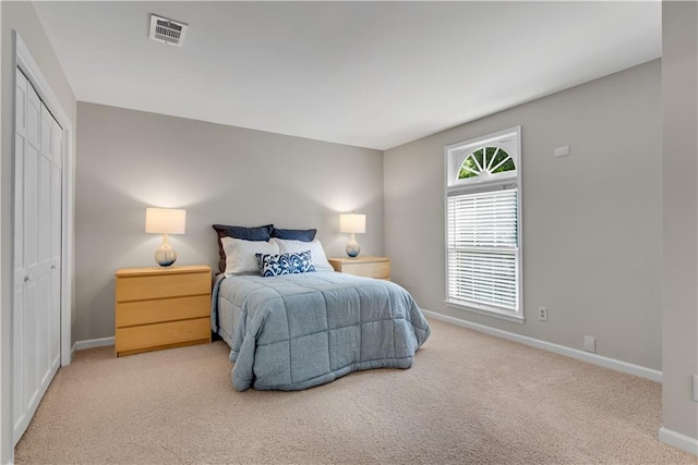 bedroom featuring a closet, light colored carpet, visible vents, and baseboards