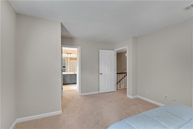 bedroom with light carpet, ensuite bathroom, visible vents, and baseboards