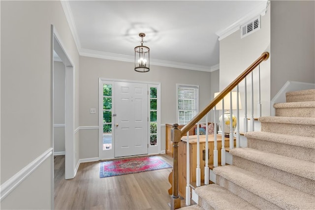 entrance foyer with stairs, ornamental molding, visible vents, and light wood-style floors