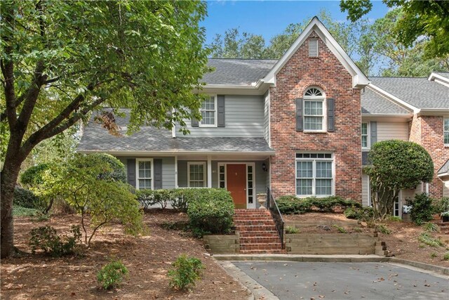 traditional home with a shingled roof and brick siding