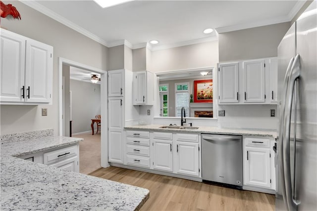 kitchen with stainless steel appliances, a sink, white cabinetry, and crown molding