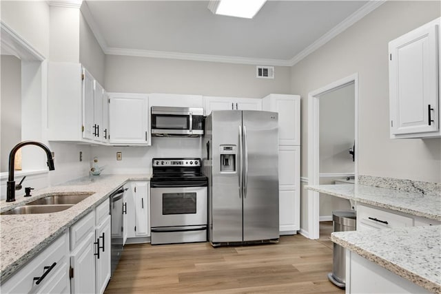 kitchen with visible vents, white cabinets, light stone counters, stainless steel appliances, and a sink