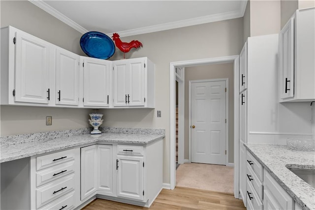 kitchen with ornamental molding, white cabinetry, and light stone countertops