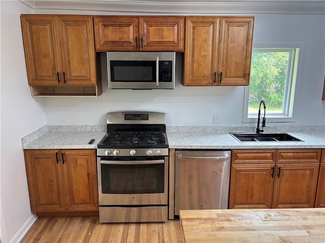 747 Bowman St, Macon, GA 31217 - kitchen with appliances with stainless steel finishes, brown cabinetry, light wood-style floors, and light stone counters