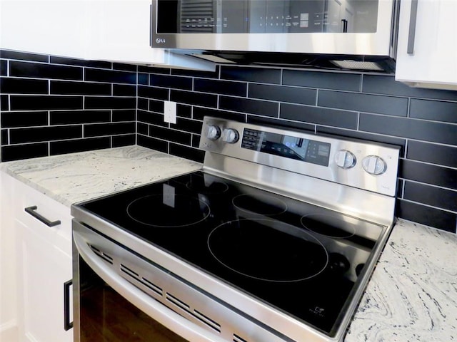 kitchen featuring tasteful backsplash, white cabinetry, light stone counters, and appliances with stainless steel finishes